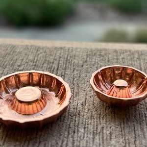 Könnte beinhalten: Zwei kupferfarbene Metallformen mit geriffeltem Design. Die größere Form ist breiter und flacher als die kleinere Form.