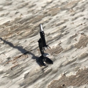 May include: A small, black and silver toy microscope. The microscope is made of metal and has a silver-colored lens.