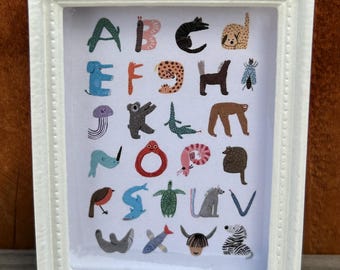 May include: A white framed print with a colorful alphabet illustrated with animals. The letters are in a playful font and each letter is paired with an animal that starts with that letter. For example, A is for alligator, B is for butterfly, C is for cat, and so on.