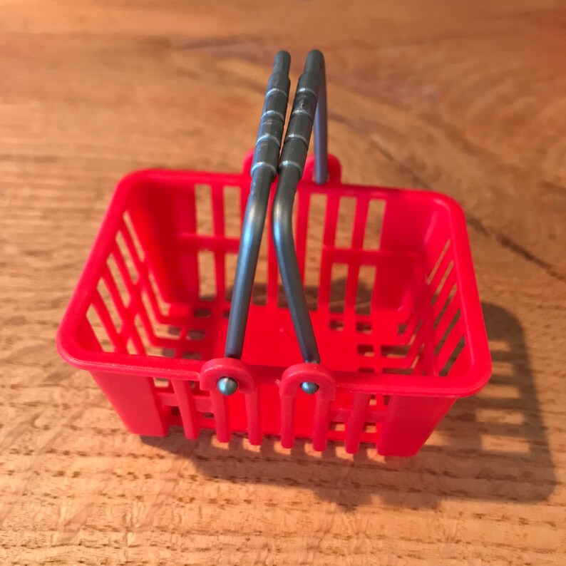 Op de afbeelding: Een klein rood plastic boodschappenmandje met zilveren metalen handvatten.