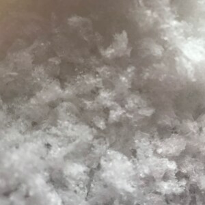 May include: Close-up of a white, grainy, textured surface. The surface is made of small, irregular crystals.