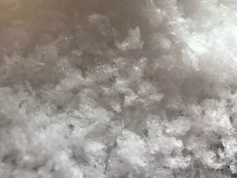 May include: Close-up of a white, grainy, textured surface. The surface is made of small, irregular crystals.