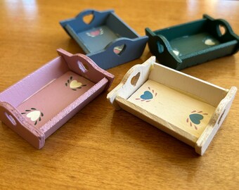 May include: Four miniature wooden trays with heart-shaped cutouts and painted hearts. The trays are painted in shades of pink, white, blue, and green.