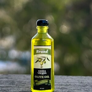 May include: A clear glass bottle of olive oil with a black cap and label. The label says "Nature Brand Extra Virgin Olive Oil Premium 450ml".