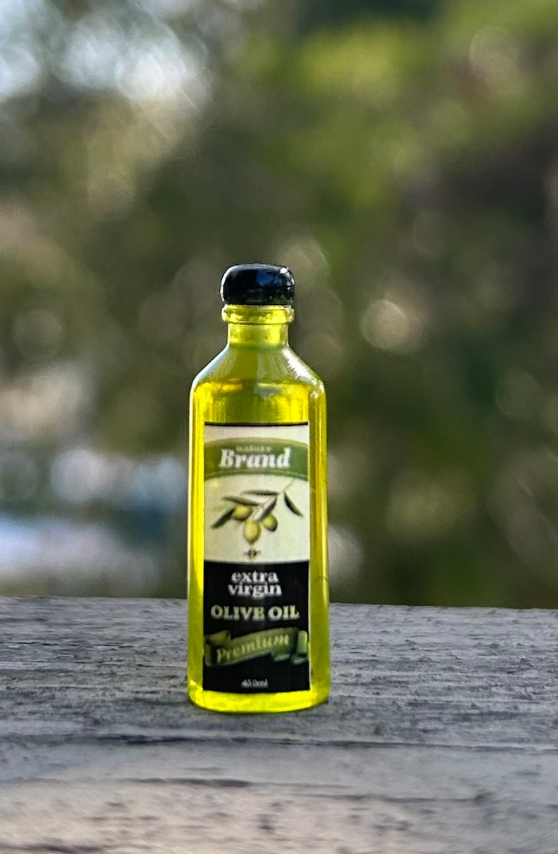 May include: A clear glass bottle of olive oil with a black cap and label. The label says "Nature Brand Extra Virgin Olive Oil Premium 450ml".