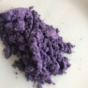 Puede incluir: Un montón de polvo de mica púrpura suelto sobre una superficie blanca.