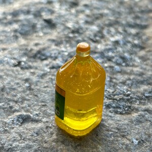 May include: A clear plastic bottle filled with yellow liquid. The bottle has a yellow cap and a green label.