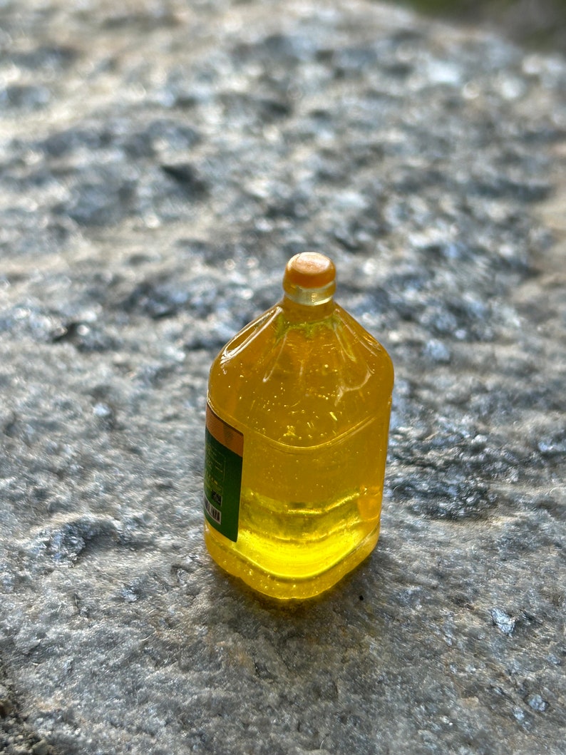 May include: A clear plastic bottle filled with yellow liquid. The bottle has a yellow cap and a green label.