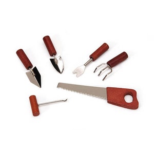 May include: A set of five miniature gardening tools with wooden handles. The tools include a trowel, a rake, a hand saw, a cultivator, and a small hand rake.