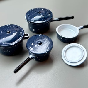 Op de afbeelding: Set van vier blauwe en witte gespikkelde emaille kookgerei. De set bevat een pan, een koekenpan, een deksel en een kleine pan.