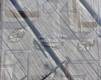 Puede incluir: Molde de plástico transparente con múltiples cavidades rectangulares. El molde está diseñado para hacer objetos pequeños, como jabón o caramelos. El molde tiene el texto "Mike Watts" y "Portland, ON" impreso en él.