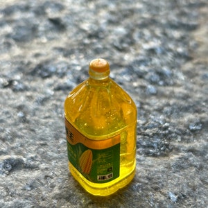 May include: A clear plastic bottle of yellow corn oil with a green label featuring a corn cob. The label has Chinese text and a barcode.