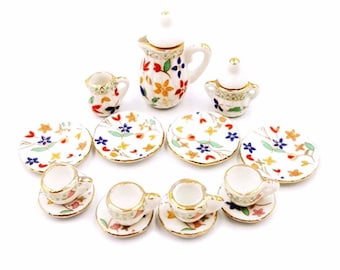 May include: A miniature porcelain tea set with a floral design. The set includes a teapot, creamer, sugar bowl, four cups, and four saucers.