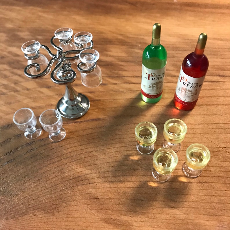 May include: A miniature wine set with a silver metal wine glass holder, six clear glass wine glasses, and two miniature wine bottles. One bottle is green and the other is red. The bottles have labels that read "Domaine Tresor".