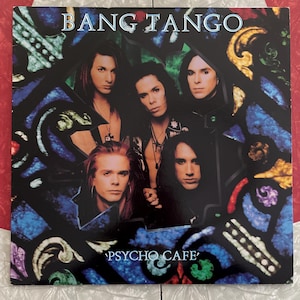 May include: A vintage vinyl record album cover featuring the band Bang Tango. The cover art is a stained glass style image of the band members with the album title "Psycho Cafe" printed below.