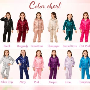 May include: A color chart displays a variety of pajama sets in different colors. The pajamas are shown in black, burgundy, cameo brown, champagne, emerald green, hot pink, silver gray, navy, pink, purple, lilac, and turquoise.