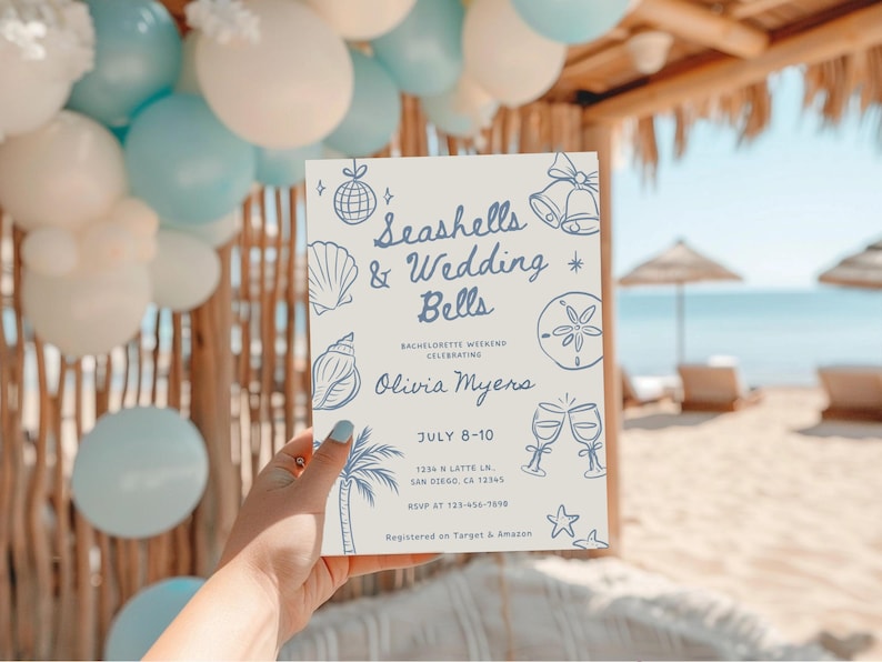 Peut inclure: Une invitation rectangulaire avec le texte "Seashells & Wedding Bells" en bleu, avec des illustrations de coquillages et de cloches. L'invitation est tenue devant une sc&egrave;ne de plage avec des ballons.