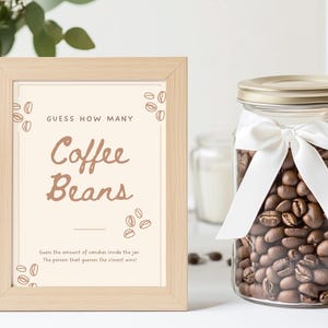 Może przedstawiać: Ramka z napisem "GUESS HOW MANY Coffee Beans" i słoik wypełniony ziarnami kawy. Słoik jest przewiązany białą wstążką.