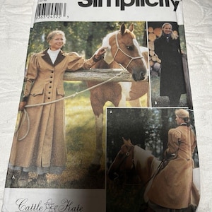 May include: A Simplicity sewing pattern envelope, number 0453, featuring Cattle Kate designs. The cover displays photographs of a long tan coat with dark lapels and a black coat, both worn with horses. The pattern includes sizes 14, 16, 18, and 20.