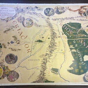 May include: A vintage-style illustrated map titled There and Back Again, A Map of Bilbo's Journey through Eriador and Rhovanion. The parchment-colored map features detailed topography, labeled regions, rivers, mountains, and circular vignettes.