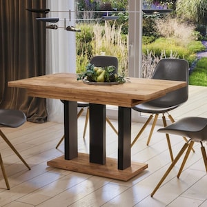 Könnte beinhalten: Ein Esstisch aus Holz mit einem schwarzen Metallgestell und vier schwarzen Stühlen mit goldenen Beinen. Der Tisch ist mit einer Schale Obst und Grünzeug gedeckt.
