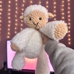 Op de afbeelding: Een handgemaakt pluche lammetjesspeelgoed met een witte body en een beige gezicht, oren en poten. Het lam heeft zwarte ogen en een gestikte mond. Het speelgoed is zacht en pluizig, perfect voor kinderen.