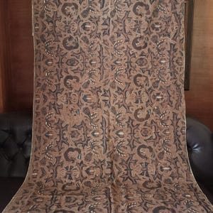 Könnte beinhalten: Ein brauner und weißer Stoff mit einem sich wiederholenden Muster aus stilisierten Blumen und Blättern. Der Stoff hat einen dezenten Glanz und eine weiche Textur.