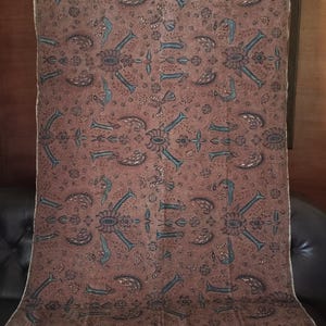 Peut inclure: Un tissu brun avec un motif floral bleu et vert répété. Le tissu a un léger brillant et une texture douce.