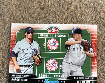 May include: A baseball card featuring two New York Yankees players, Aaron Judge and Ian Clarkin, in their uniforms. The card has a green and red design with the text "DRAFT" and "Bowman".
