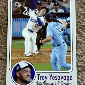 May include: Baseball card featuring a baseball player in a Dodgers uniform, mid-swing. The card includes a portrait of Trey Yesavage and text that reads "Sets Rookie WS Record."
