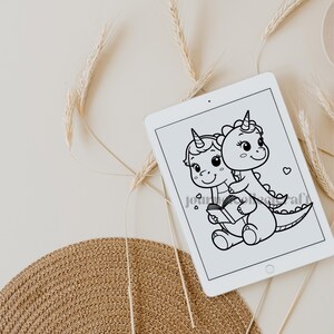 May include: Black and white line art illustration of a unicorn and a dinosaur holding a book. The unicorn is sitting on the dinosaur's back. The dinosaur has a long tail and a small horn on its head. The unicorn has a long horn and a mane. The book is open and has a heart on the cover.