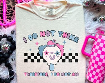 May include: A white t-shirt with a pink, blue, and white graphic of a clown with the text "I do not think therefore, I do not am".