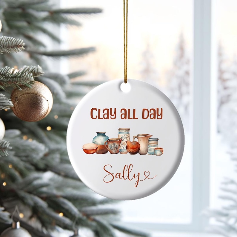 Pu&ograve; includere: Ciondolo in ceramica bianca con una scritta marrone che recita "Clay all day Sally" e un'illustrazione ad acquerello di ceramiche.