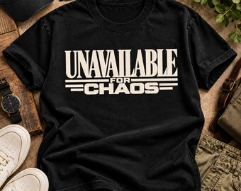 Può includere: Una t-shirt nera a maniche corte con il testo bianco UNAVAILABLE FOR CHAOS stampato in un carattere grassetto e stilizzato sul petto, con linee orizzontali che accentuano la parola CHAOS sul tessuto scuro.
