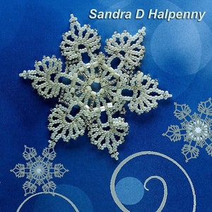 Puede incluir: Un diseño detallado de copo de nieve con cuentas plateadas y blancas. La imagen incluye el texto "Sandra D Halpenny". El copo de nieve está sobre un fondo azul con remolinos decorativos.