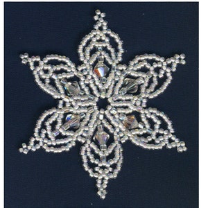 Puede incluir: Primer plano de un adorno de copo de nieve plateado hecho con cuentas. El copo de nieve tiene 6,3 cm de diámetro. La leyenda dice "Bead Store - 2-1/2" Snowflake" A = Miyuki 11° SEED bead, 450 beads T = Miyuki 10° Triangle bead, 36 beads C = 6 mm crystal, 6"