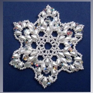 May include: White snowflake ornament pattern, made with white beads and iridescent crystals. The pattern is called "Snowflake #119 Ornament Pattern" and is by Sandra D Halpenny.