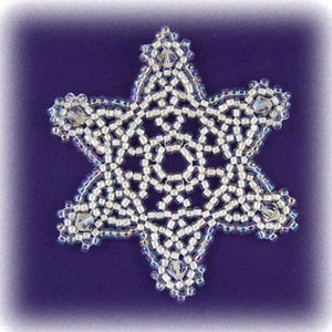 Puede incluir: Un patrón de adorno de copo de nieve blanco con instrucciones para el abalorio. El patrón utiliza cuentas Miyuki 11° SEED, cristales de 4 mm, hilo Nymo D o Fireline y una aguja de abalorios n.º 11 o n.º 12.