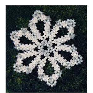 Puede incluir: Un patrón de adorno de copo de nieve de cuentas blancas, con el texto "Snowflake #189 Ornament Pattern" y "Design by Sandra D. Halpenny".