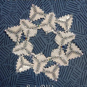 Puede incluir: Adorno de copo de nieve hecho a mano, con cuentas. El adorno blanco presenta un diseño circular con seis formas de copo de nieve. El texto "Snowflake #193 Ornament" y "Sandra D Halpenny" son visibles.