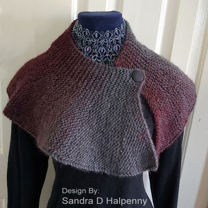 Peut inclure: Un col roul&eacute; en tricot gris et bordeaux avec une fermeture &agrave; bouton unique. Le col est drap&eacute; sur un mannequin portant une chemise noire et un collier de perles. Le texte "Design By: Sandra D Halpenny" est en bas de l'image.