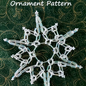 Puede incluir: Un patrón de adorno de copo de nieve hecho a mano, con cuentas, con un diseño delicado e intrincado. El copo de nieve es blanco con acentos iridiscentes, sobre un fondo verde. El texto dice "Snowflake #71 Ornament Pattern" y "Sandra D Halpenny".