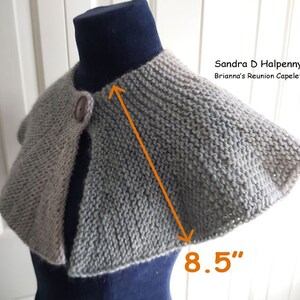 Peut inclure: Un capuchon en tricot gris et beige avec une fermeture &agrave; bouton. Le capuchon mesure 8,5 pouces de large. "Sandra D Halpenny Brianna's Reunion Capelet" est &eacute;crit sur l'image.