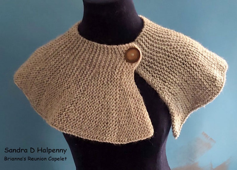 Peut inclure: Un capuchon en tricot beige avec un seul bouton en bois. Le capuchon est drap&eacute; sur un mannequin noir.