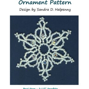 Puede incluir: Un patrón de adorno de copo de nieve de cuentas blancas, con el título "Snowflake #18 Ornament Pattern" y el texto "Design by Sandra D. Halpenny". El patrón utiliza cuentas Miyuki 11° SEED y cristales Fire-polished de 4 mm.
