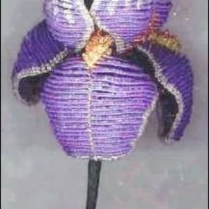 May include: A purple and white crocheted iris flower with a brown center. The flower is on a black stem.