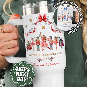 May include: White tumbler featuring a Nutcracker ballet design with a red bow, stars, and ribbon accents. The tumbler includes the text "THE NUTCRACKER 2025" and "Lee as Clara". A smaller image shows six color options. The tumbler has a handle and a straw.