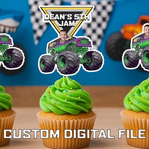 May include: Cupcakes with green icing and colourful sprinkles, topped with monster truck toppers. The toppers feature a child in a monster truck with the text "DEAN'S 5TH JAM". The cupcakes are on a wooden surface.