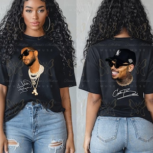 May include: A black short-sleeve t-shirt featuring a graphic print of a man wearing sunglasses and layered gold chains on the front, and a graphic print of a man wearing a black baseball cap and sunglasses on the back, with signatures included.