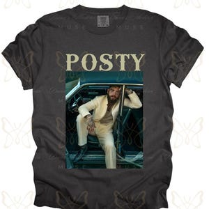 May include: A dark gray t-shirt with a white graphic of a man in a white suit sitting in a car. The text "POSTY" is printed in white above the graphic.